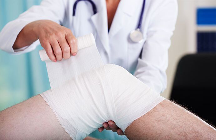 The doctor wraps the knee joint with arthrosis